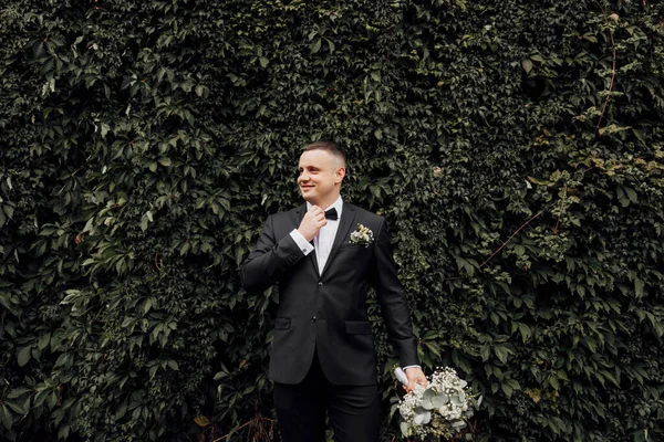 Lycklig Brudgum Svart Kostym Med Bukett Blommor Handen Justerar Sin — Stockfoto