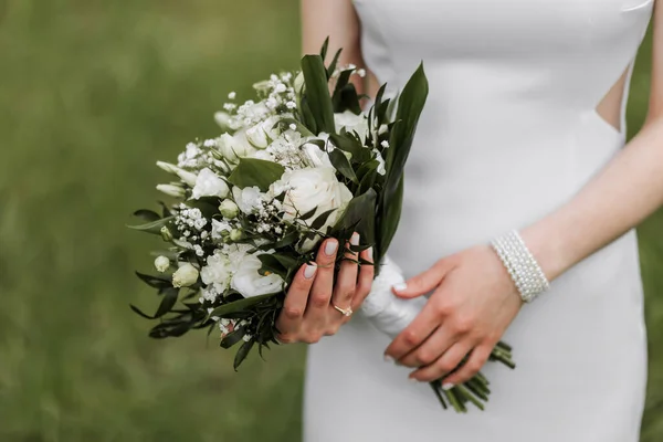 新娘手里拿着一束漂亮的婚礼用的白花 白色晚礼服 手上有漂亮的珠宝 — 图库照片