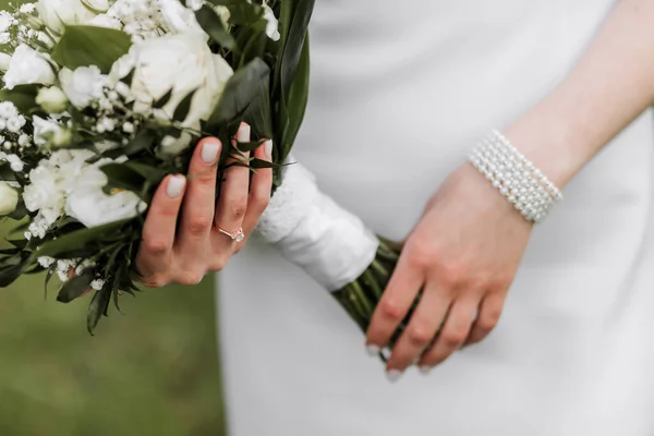 新娘手里拿着一束漂亮的婚礼用的白花 白色晚礼服 漂亮的珠宝在她的手上 把重点放在结婚戒指上 — 图库照片