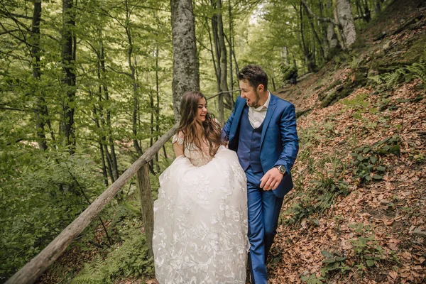 一对幸福的新婚夫妇正沿着森林小路奔跑 新郎和新娘 婚礼照相会在自然界 在新娘和新郎的森林里拍照 — 图库照片