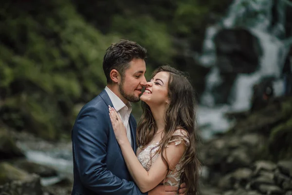 滝の近くに幸せな花嫁と新郎の肖像画 花嫁と新郎 自然の中で結婚式の写真セッション 新郎新婦の森での撮影会 — ストック写真