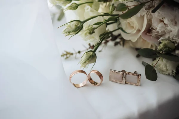 ピンクと白の花と白の背景に2つの金の結婚指輪とカフスボタン ウェディングアクセサリー — ストック写真