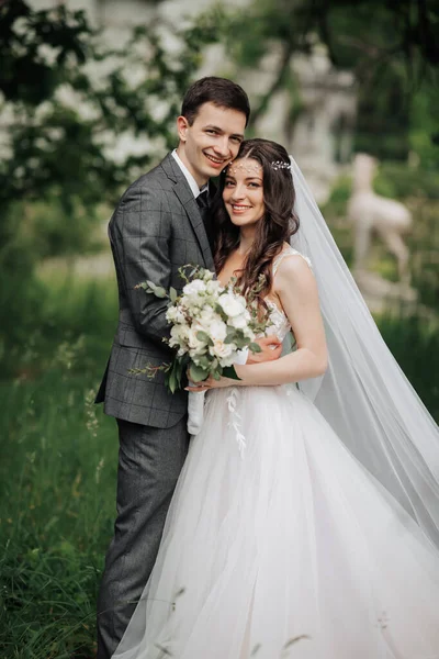 Happy young couple. Wedding portrait. The bride tenderly hugged the groom. Young brides and grooms are tenderly embracing while looking at the camera. Wedding bouquet. Spring wedding