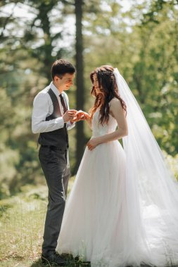 Tarz sahibi genç gelinler, mutlu günlerinde, birbirlerinin keyfini çıkarırlar. Damat gelinin alyansını takar. Portre. Bahar düğünü. Doğal makyaj.