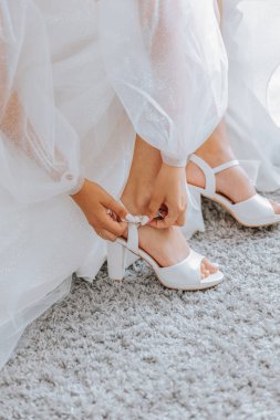 Gelin beyaz ayakkabılarını giyiyor. Güzel gelin düğüne hazırlanıyor. Ayakkabı deneyen bir kadın.