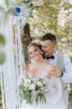 Düğün günü damat ve gelin, dışarıda yürüyüş. Damat geline omuzlarından sarılıyor. İnsanlar mutlu ve gülümsüyor. Birbirini seven mutlu çift birbirine bakıyor.