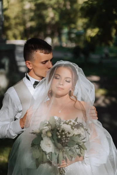 婚礼时刻 年轻夫妇 新娘和新郎在阳光下亲吻着面纱 一个吻 一对年轻夫妇 — 图库照片