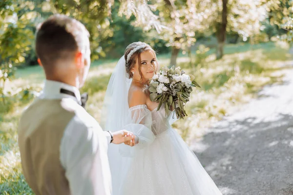 결혼식 사랑에 아름다운 커플의 신부는 햇빛을 받으며 공원을 산책하면서 신랑을 — 스톡 사진
