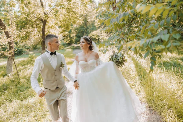 결혼식 사랑에 아름다운 커플의 신랑은 햇빛을 받으며 공원을 산책하면서 신부를 — 스톡 사진