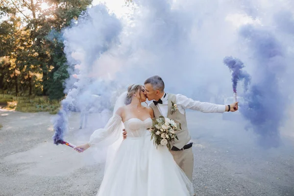 Ich Rękach Nowożeńcy Trzymają Wielobarwne Bomby Dymne Kolorze Niebieskim Pocałunek — Zdjęcie stockowe