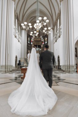 Lviv. Burası büyük bir Katolik kilisesi, şehrin ana merkezi. Parlak kilisenin içi, geniş kolonlardan oluşan bir manzara. Düğün törenindeki gelin ve damat, arkadan çekilen fotoğraf.
