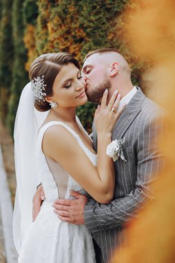 Gelin ve damat birbirlerine nazikçe sokuldular. Bir çift yeni evli, gelin ve damat, yeşil ağaçların doğasında bir düğünde. fotoğraf portresi Düğün çifti