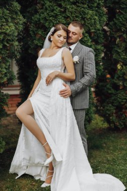 Gelin, elinde buketle damadın nazikçe kucağında. Mutlu evlilik çifti kutlamanın tadını çıkarıyor. Gelin ve damadın portresi.