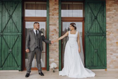 Gelin ve damat yeşil pencerelerin arkasında duruyorlar. Şık gelin ve damat. Düğün fotoğrafı. kolay atmosfer