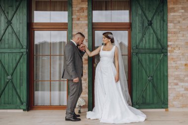 Gelin ve damat yeşil pencerelerin arkasında duruyorlar. Şık gelin ve damat. Düğün fotoğrafı. kolay atmosfer