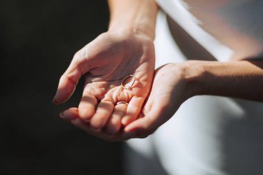 Beyaz elbiseli ve güneş gözlüklü bir kadının elindeki zarif elmas yüzüğün yakın çekimi. Aşk ve düğün kavramı. yumuşak ve seçici odaklanma.