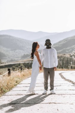 Beyaz gömlekli şık damat ve düğün kemerinin yanındaki ormanda beyaz elbiseli güzel esmer gelin. Yeni evlilerin düğün portresi..