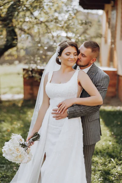 Gelin, elinde buketle damadın nazikçe kucağında. Mutlu evlilik çifti kutlamanın tadını çıkarıyor. Gelin ve damadın portresi.