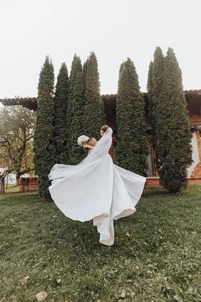 Jóképű Vőlegény Egy Gyönyörű Nevető Menyasszonyt Cipel Karjaiban Egy Tavaszi — Stock Fotó