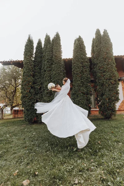 Jóképű Vőlegény Egy Gyönyörű Nevető Menyasszonyt Cipel Karjaiban Egy Tavaszi — Stock Fotó