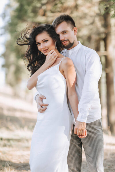 Young happy couple in love hugging smiling and having fun in the mountains. High quality photo. A girl in a beautiful white dress. Portrait photo