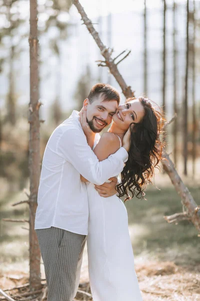 白いシャツのスタイリッシュな新郎と結婚式の木製のアーチの近くの森の中で白いドレスでかわいいブルネットの花嫁 新婚の結婚式の肖像画 — ストック写真