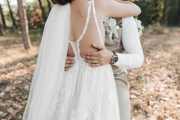 婚纱照在自然界 新娘拥抱新郎 新郎的手放在新娘的腰部 新娘美丽的双肩 — 图库照片