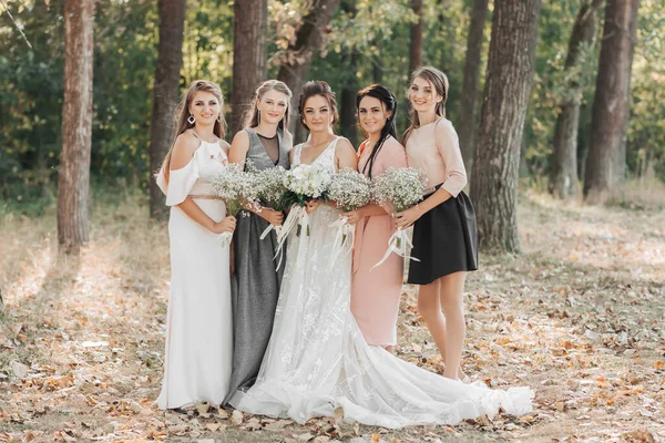 婚纱照在自然界 新娘和伴娘们笑着站在森林里 捧着她们的花束 看着镜头 结婚快乐的概念 — 图库照片