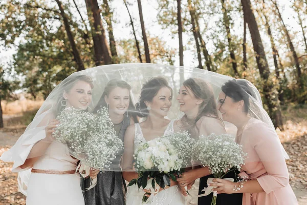 自然の中で結婚式の写真 花嫁と彼女の友人たちは 花嫁のベールに覆われた笑顔で 花束を持って森の中に立っています 結婚式の肖像画 感情だ 美しい女の子 — ストック写真