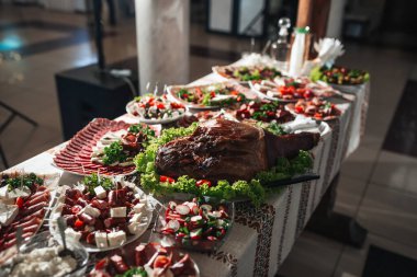 Düğünde büfe masası. Ukrayna tarzı masa örtüsünün üzerinde duran beyaz tabaklar üzerinde çeşitli atıştırmalıklar. Ziyafet servisi. Yiyecek, peynir, jambon, jambon ve yeşillik..