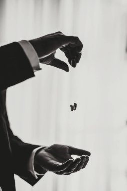 Adamın elinde iki tane alyans var. Damat alyansları atıyor. Damat yüzükleri tutar. Düğün gelenekleri. Altın yüzükler bir insanın avucunda bulunur. Siyah beyaz fotoğraf.