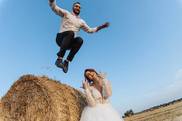 Foto Casamento Noivo Elegante Uma Camisa Branca Salta Fardo Feno — Fotografia de Stock