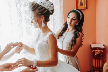 bride's girlfriend prepares the bride for her wedding day. The bride's girlfriend helps secure the bride's wedding dress before the ceremony. clipart