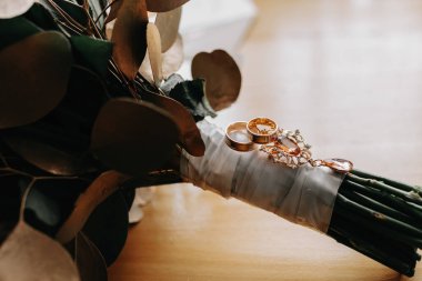 Damadın düğünü için aksesuarlar. Damadın lüks buketi. Altın düğün davetiyesi, altın yüzükler, tahta zemin üzerinde kol düğmeleri. Erkek modası