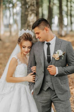 Gelin ve damat bir peri masalı ormanının arka planında. Kraliyet düğünü konsepti. Damat gelini kucaklıyor. Şefkat ve sakinlik. Portre fotoğrafı