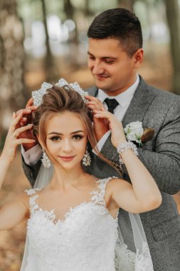 Gelin ve damat bir peri masalı ormanının arka planında. Kraliyet düğünü konsepti. Damat gelinin tacını takar. Şefkat ve sakinlik. Portre fotoğrafçılığı