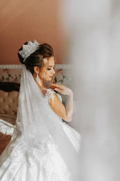 新娘穿着漂亮的衣服站在窗边 照片来自婚礼的背面 婚礼花束新娘的早晨 一个艺术婚礼 一个快乐的新娘在等新郎 — 图库照片