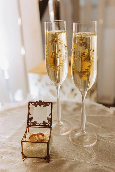 ウェディンググラスはシャンパンで満たされています ウェディングリングと結婚式の準備 美しい光 — ストック写真