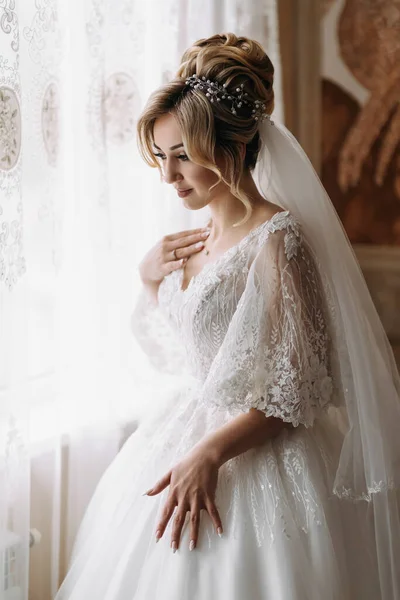 Okna Pózuje Blonďatá Nevěsta Bílých Šatech Dlouhém Závoji Krásné Ruce — Stock fotografie