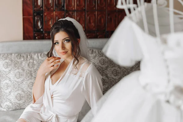 Uma Noiva Morena Vestido Vestir Senta Sofá Cinza Segurando Seus — Fotografia de Stock