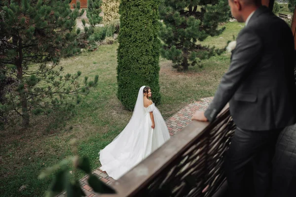 Svatební Fotka Nevěsta Objemných Bílých Šatech Dlouhém Závoji Kráčí Zahradou — Stock fotografie