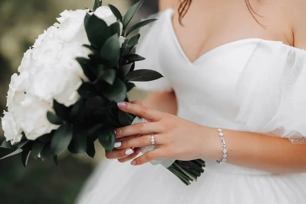剪过的照片新娘穿着一条带领口的白色连衣裙 手里拿着一束白玫瑰 美丽的手和银珠宝 法国修指甲 新娘的肖像 — 图库照片