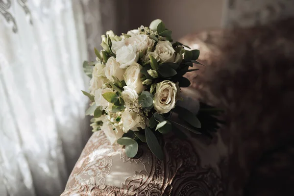 新郎婚礼的配件 靠窗的沙发后面立着一束白玫瑰和绿叶 美丽的花朵光线和阴影 — 图库照片