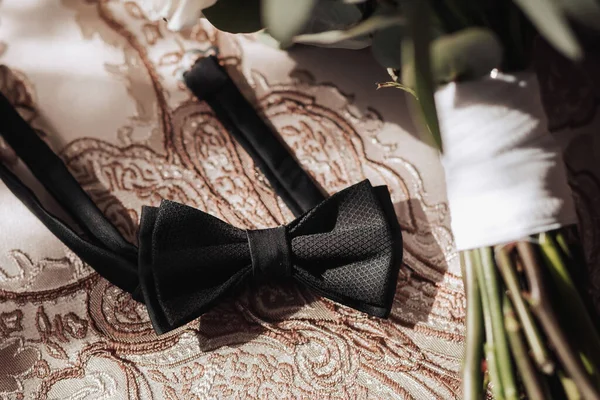 男人的配饰黑色丝绸领结在漂亮的金桌布上 光线和阴影 婚礼的细节 男人的风格 — 图库照片