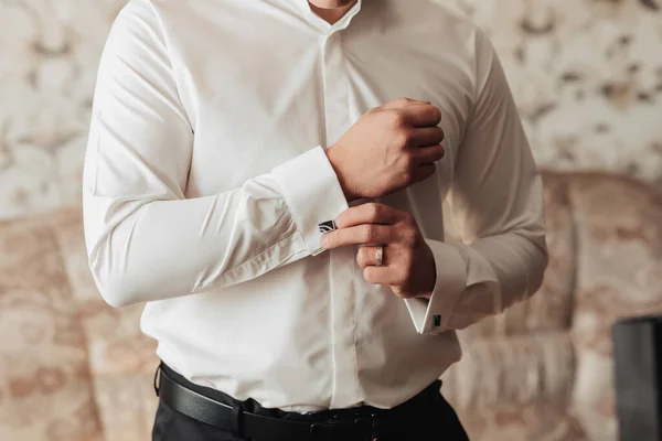 照片细节 一个男人把纽扣系在一件白衬衫的袖子上 前面的景色天亮了时尚和时尚 男人的风格 美丽的手 — 图库照片