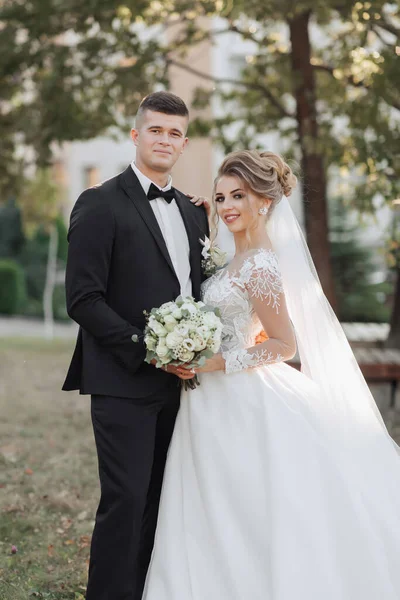 Γαμήλιο Πορτρέτο Γαμπρός Μαύρο Κοστούμι Και Ξανθιά Νύφη Στέκονται Αγκαλιασμένοι — Φωτογραφία Αρχείου