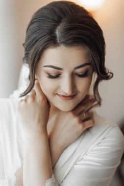 Yüzüne dokunan esmer bir gelin portresi. Harika bir makyaj ve saç. Gönüllü duvak. Düğün fotoğrafı. Güzel gelin.