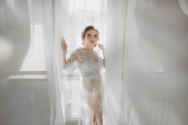 Güzel gelin. Beyaz bir arka planda düğün saç stili. Genç ve güzel bir gelinin yakın plan portresi. Düğün için. Duvağa sarılmış güzel bir gelinin portresi