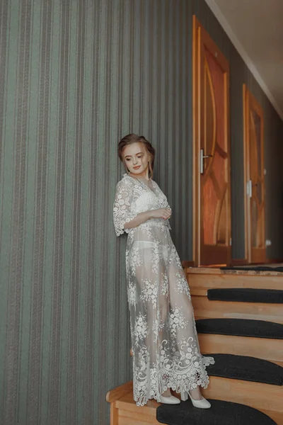 一件精致的婚纱挂在房子走廊的漂亮栏杆上 新娘穿着一件精致透明的衬裙站在台阶上 漂亮的光 婚纱照高质量的 — 图库照片