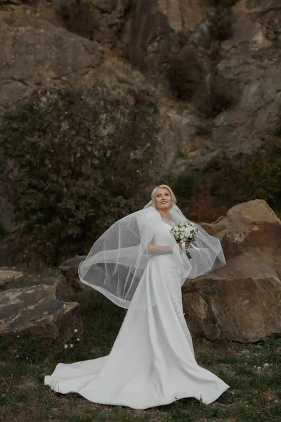 新娘站在高山上的一块岩石旁边 旁边有一块大石头 风撕破了面纱 — 图库照片